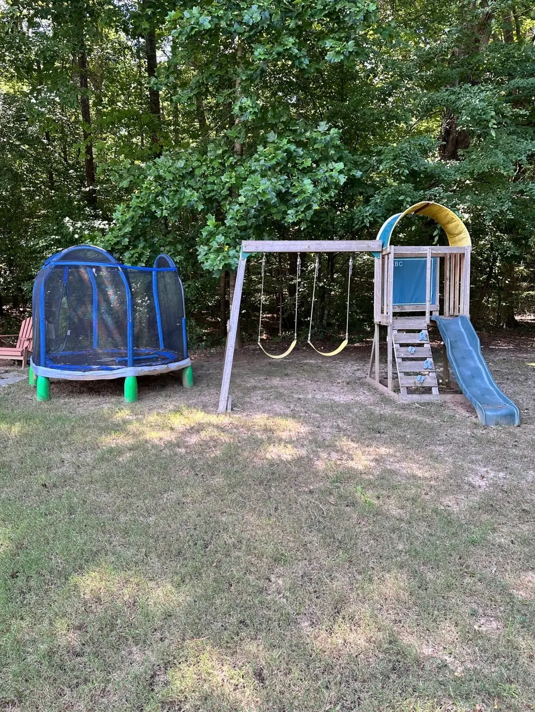 Wooden playset and trampoline in a Woodstock backyard before removal
